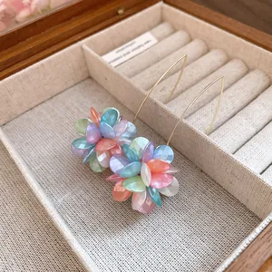 Detailed macro view of colorful pastel flower ball drop earrings in a wooden box
