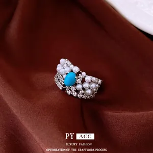 Vintage silver ring with oval turquoise stone, pearls, and zircons on brown fabric