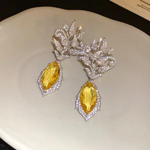 Makroansicht luxuriöser 18K vergoldeter Blumenohrringe mit funkelnden gelben Zirkonia.
