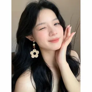 Detailed close-up of a bohemian woven rattan flower earring worn by an Asian model