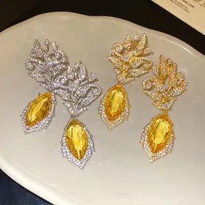 Nahaufnahme der exquisiten 18k vergoldeten Blumenohrringe mit gelben Zirkonia-Anhängern.