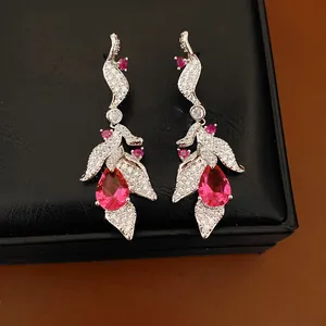 Detailed view of elegant silver earrings with pear-shaped pink stones and zircon leaves