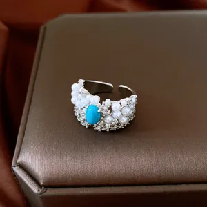 Macro detail of vintage silver-tone ring featuring turquoise, pearls, and zircons