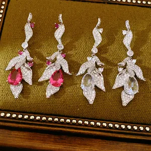 Close-up of elegant leaf-shaped earrings with teardrop zircon stones in red and clear