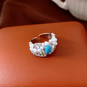 Detailed view of a vintage oval ring with pearls, zircons, and a turquoise stone.