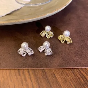 Elegant 18K gold plated bow knot stud earrings with faux pearl and crystal detailing.