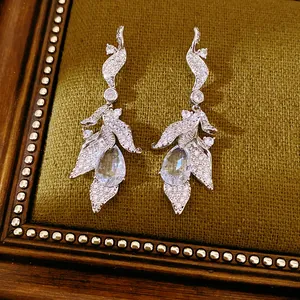 Detailed view of elegant silver leaf earrings with shimmering teardrop stones.