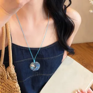 Summer light blue cord necklace with a clear pearl and sea shell pendant for women.