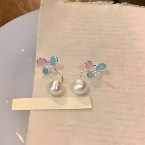 Detailed macro view of colorful butterfly zircon ear studs with elegant white pearl dangles