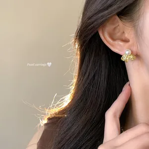 Detailed view of 18K gold plated pearl stud earrings with bow design on a model