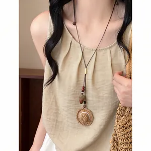 Gros plan d'un collier tissé à la main avec un pendentif miniature en forme de chapeau de paille