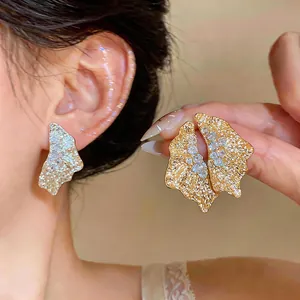 Detailed close-up of 18k gold plated wrinkled metal stud earrings with sparkling zircons