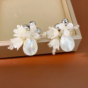 Detailed view of elegant white shell flower earrings with pearlescent water-drop charms