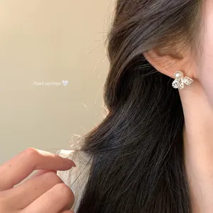 Close-up of elegant 18K gold plated pearl bow earrings worn by a model in soft light
