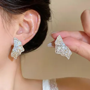 Detailed macro view of 18k gold plated crumpled texture stud earrings featuring zircons