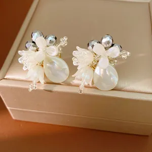 Close-up of elegant flower stud earrings with white petals and teardrop shell pearls