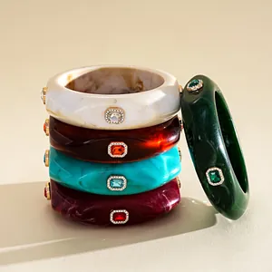 Close-up of retro resin bangles with marbled patterns and square inlaid colorful gemstones