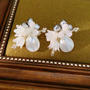 Elegant white glass shell flower earrings featuring teardrop pearl pendants in macro view