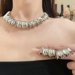 Detail view of bold metallic textured collar necklace with matching earrings on model