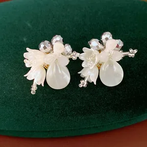 Detailed view of white shell flower earrings with crystal beads and teardrop elements
