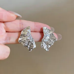 Macro view of textured silver fan earrings featuring sparkling cubic zirconia stones.