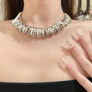 Macro view of a chunky textured silver metal choker necklace worn by a model