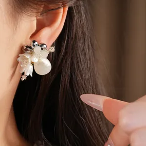 Close-up detail of elegant handmade glass shell flower earrings with teardrop pearls