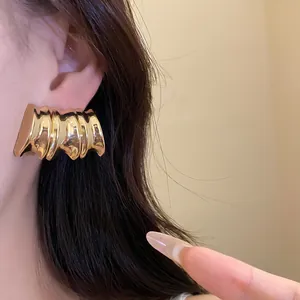 Close-up detail of a vintage gold-toned ribbed wave metal stud earring worn on the ear