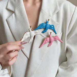 Elegant enamel swallow bird brooches in vintage gold-tone style on a white blazer
