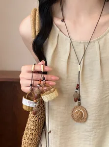 Détail du collier ethnique fait main avec pendentif mini chapeau de paille et gland
