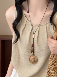 Détail d'un collier ethnique fait main avec pendentif chapeau de paille et gland.
