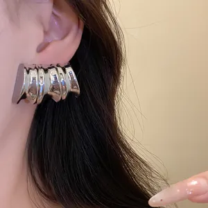 Detailed close-up of vintage style textured silver metal earrings worn on a person's ear