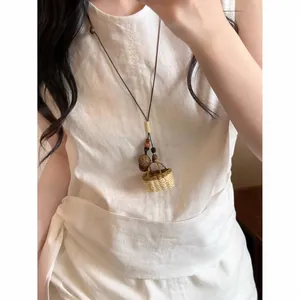 Détail d'un collier ethnique tissé à la main avec un petit pendentif panier en paille.