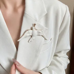 Elegant metal enamel swallow bird brooch pinned on white blazer lapel for women