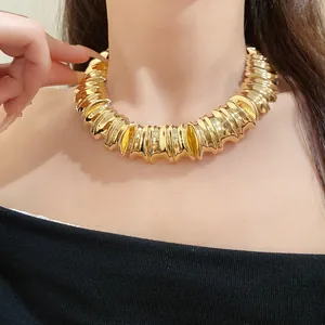 Macro view of a chunky vintage gold ribbed metal collar necklace on a female model's neck.