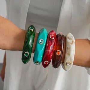 Vintage resin bangles with square rhinestones worn on a female wrist in detail view