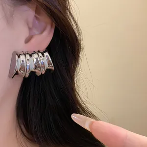 Detail shot of a vintage-style metallic wavy silver stud earring worn on a model's ear