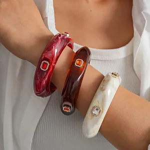 Close-up of resin bangles with square crystal embellishments on wrist