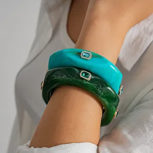 Detail of vintage marbled resin bangles with inset rhinestones and faceted gemstones.