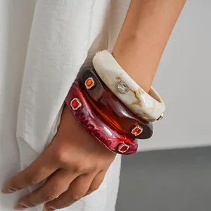Close-up of retro chunky resin bangles with square gemstone inlay and marbled texture
