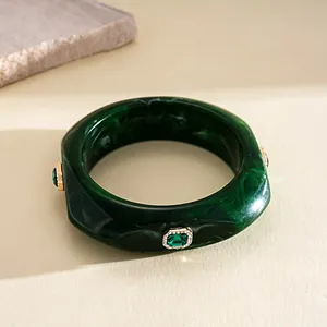 Macro shot of a dark green marbled resin bangle with emerald-cut crystal details
