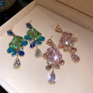 Macro detail of vintage style square crystal drop earrings in green and pink