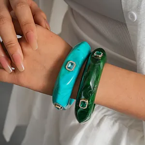 Detailed view of marbled resin bangles with crystal-encrusted geometric gold settings.