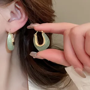 Close-up detail of green jelly resin U-shaped hoop earrings being worn on the ear