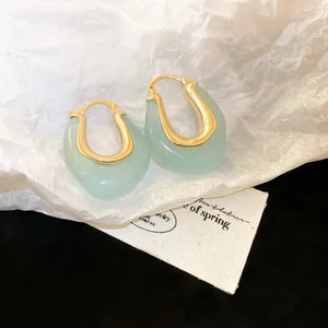 Close-up detail of U-shaped hoop earrings featuring light green jelly resin and gold accents