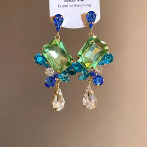 Detailed view of vintage crystal drop earrings featuring large green square gems and blue stones.