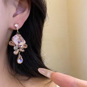 Close-up of vintage square pendant earrings with pink rhinestones on a model's ear