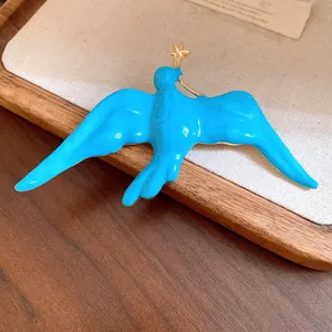 Detail of a vibrant blue enamel swallow brooch with a delicate gold star accent