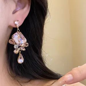 Close-up of elegant pink crystal pendant earrings with vintage square rhinestones