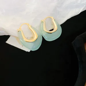 Detail view of elegant light green jelly resin U-shaped hoop earrings with gold-toned metal.